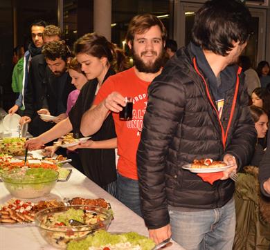 International students are loading different dishes onto their plates at a diverse buffet.